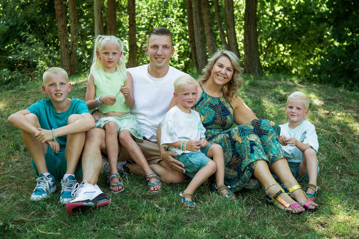 Zittend gezinsportret in het groen tijdens buitenfotoshoot in Gouda