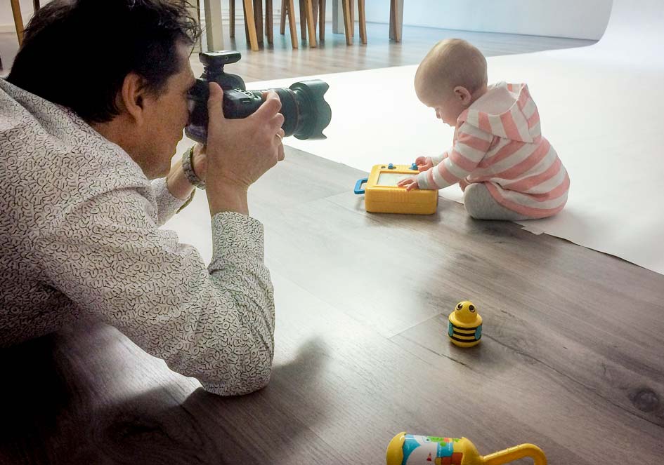 Francis fotografeert een klein kind dat op de studiovloer speelt